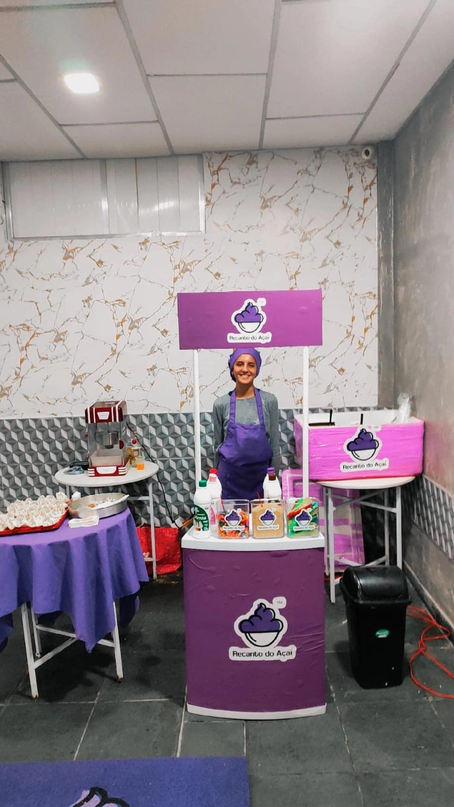 Estação de açaí montada com atendente uniformizada servindo em um evento no Rio de Janeiro